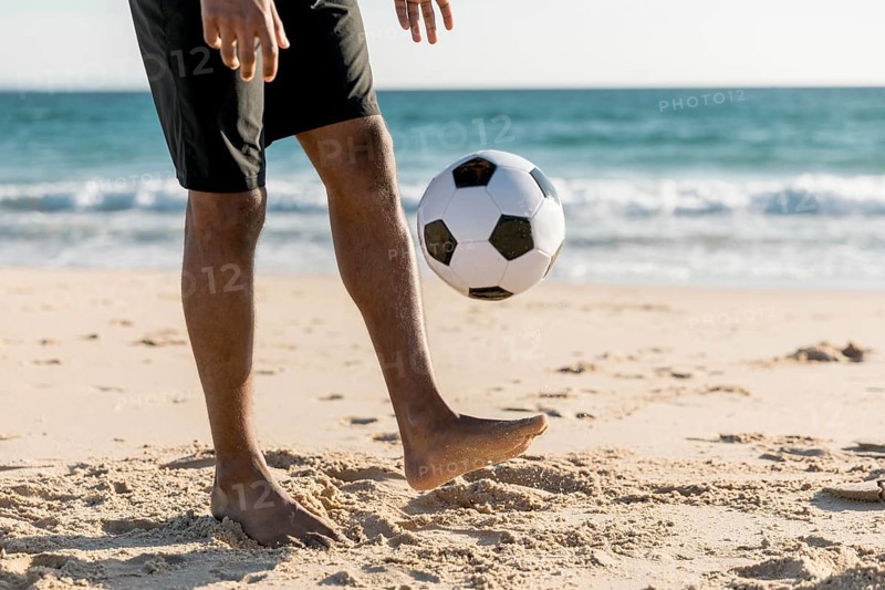 Male tossing ball up playing game beach
