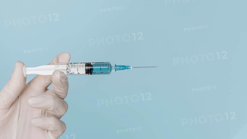 Hand with glove holding syringe