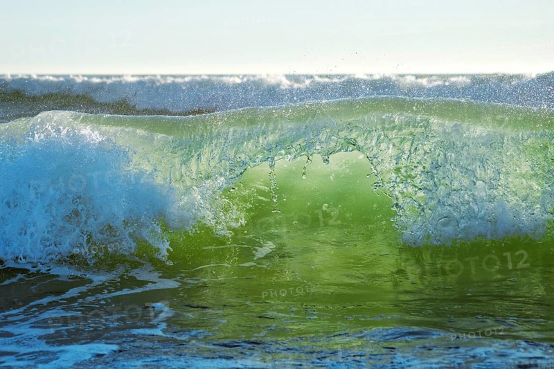 Breaking ocean wave on sunset backlit with sun. Fonte da Telha