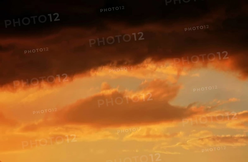 Cloudy sky at sunset. The sky is visible through a gap in the clouds. The image conveys a mood of an impending storm or bad weather