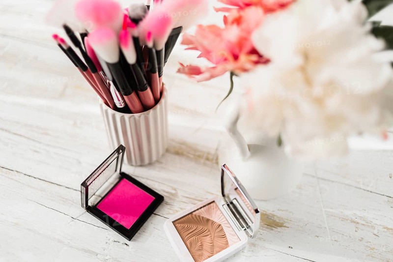 Cosmetics brushes near flowers