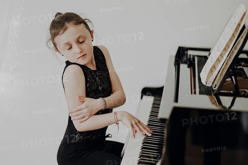 Elegant girl sits at a concert grand piano and plays the piano