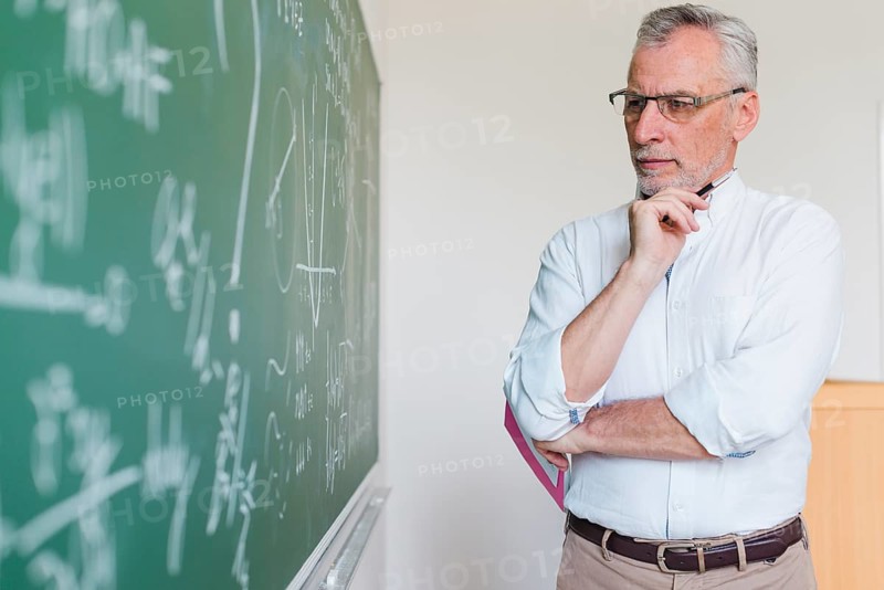 Aged math teacher thinking chalkboard