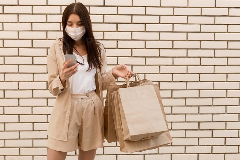 Woman holding shopping bags wearing mask front view
