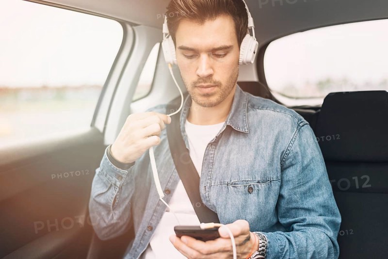 Young man listening music headphone while travelling car