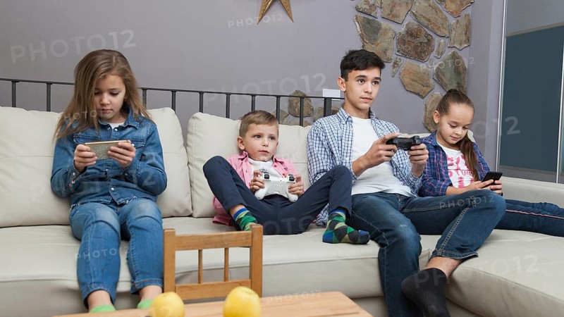 Boys playing video games girls using smartphones