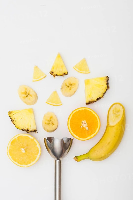 Electric blender with pineapple banana orange slices isolated white background