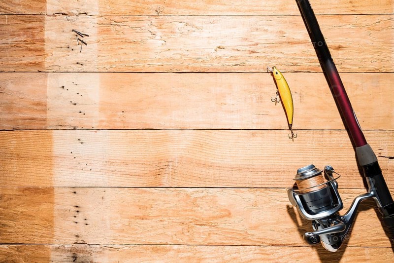 Fishing rod with yellow fishing bait wooden plank