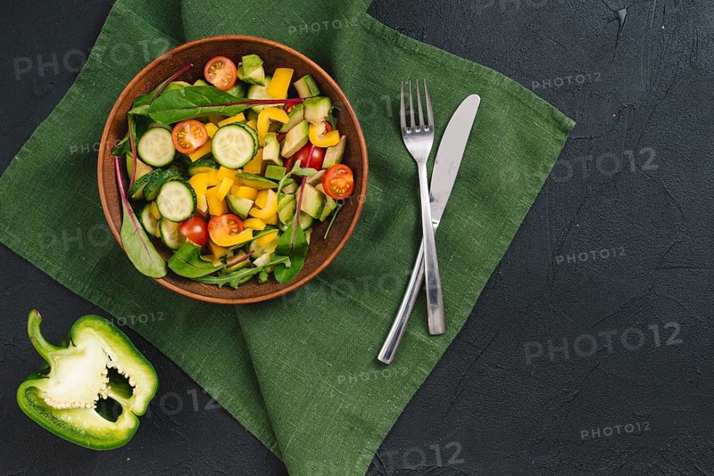 Halved bell pepper mixed vegetable salad green napkin black concrete backdrop