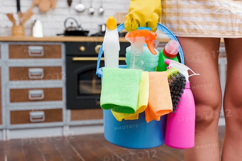 Female janitor holding cleaning accessories bucket standing kitchen