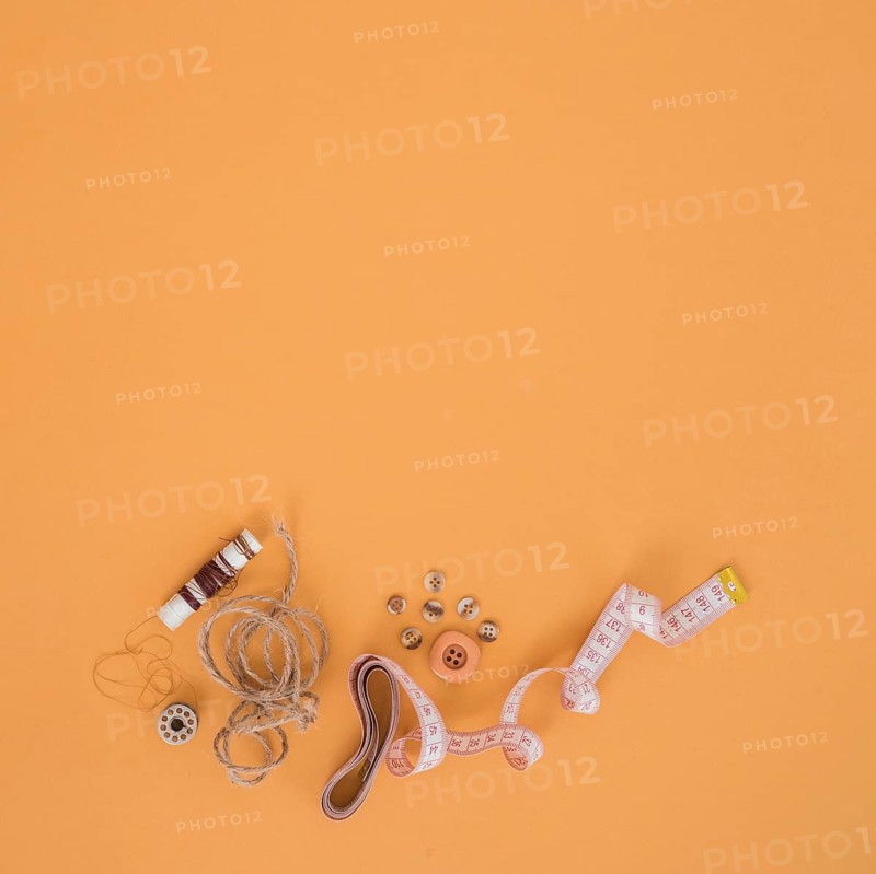 Brown spool string buttons measuring tape orange backdrop