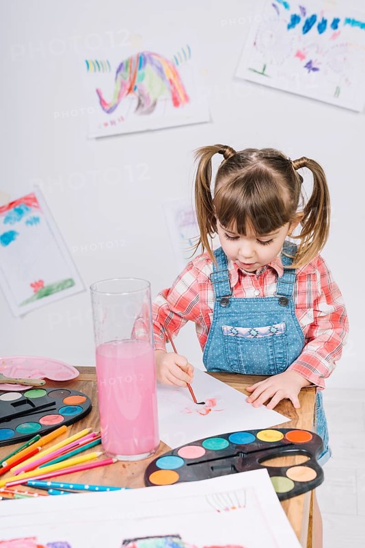 Cute girl painting with aquarelle paper