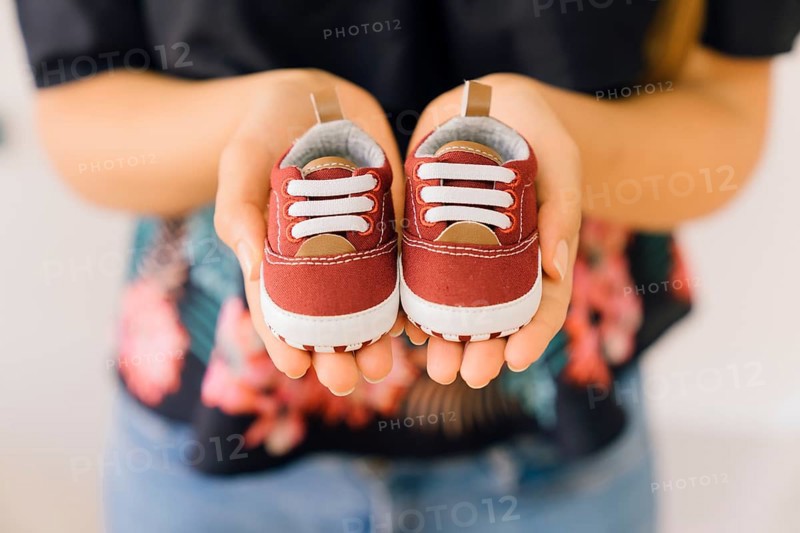 Newborn concept with woman with little shoes hands