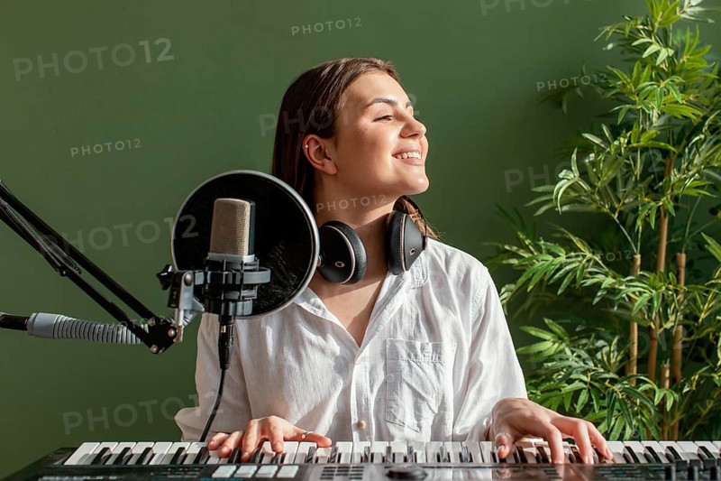 Front view smiley female musician playing piano keyboard indoors