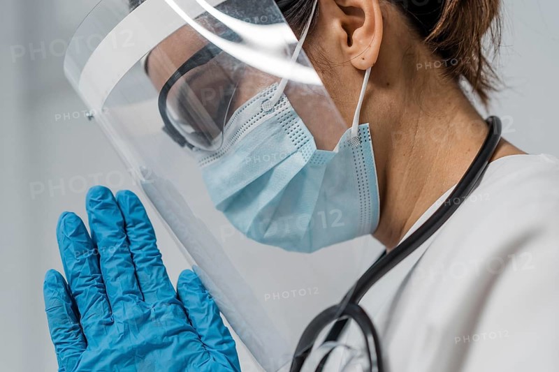 Side view female doctor with face shield medical mask praying