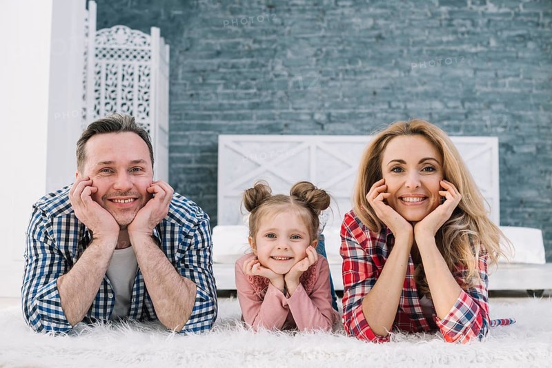 Joyful cute family lying carpet looking camera