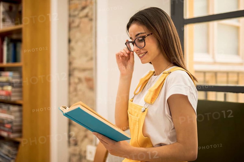 Attractive young woman reading book library