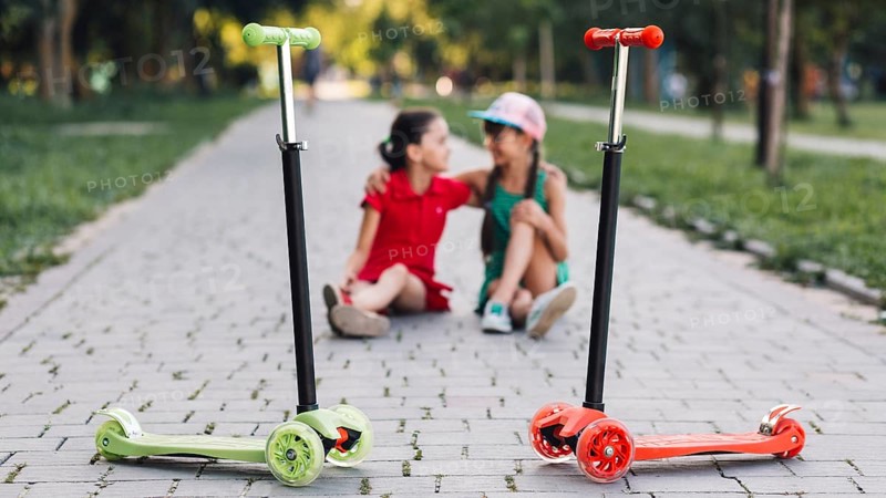 Push scooters front girls sitting walkway park
