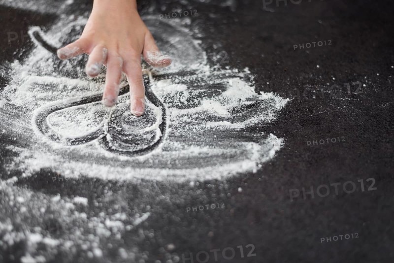 Close up girl s hand drawing heartshape flour