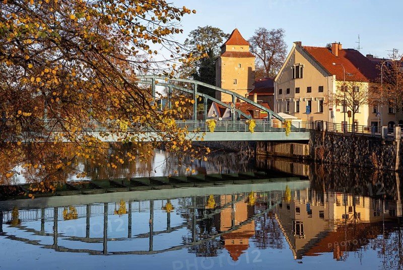 Autumnal coloured trees with iron bridge over the river Maltsch with the city wall of the historical old town of Ceske Budejovice