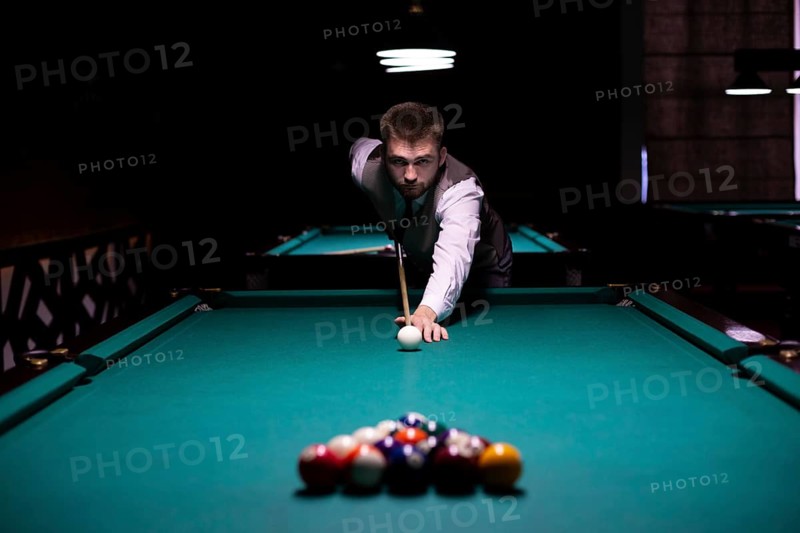 Medium shot guy with pool cue hitting white ball