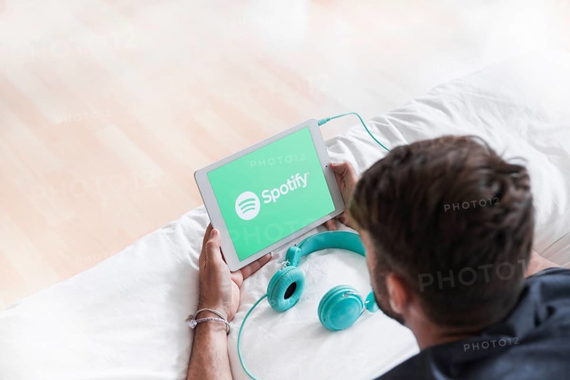 Young man holding modern device with spotify app