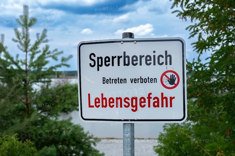 Sign with the inscription Sperrbereich Betreten verboten Lebensgefahr on the shore of Lake Senftenberg