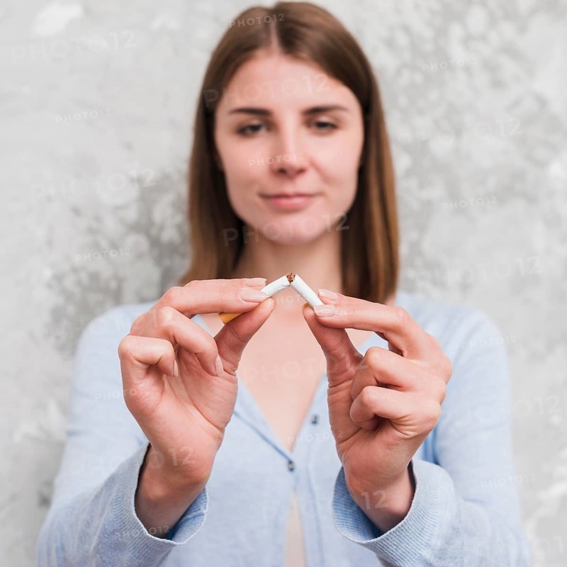 Portrait young woman breaking cigarette