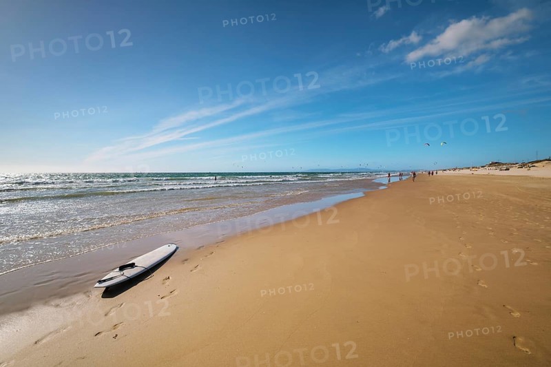 Sandy Atlantic ocean beach with surfboard at Fonte da Telha beach