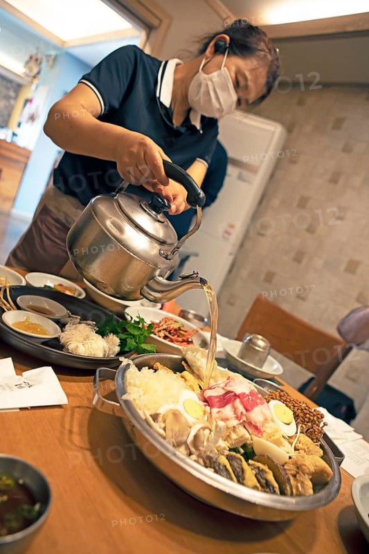 Korean woman pouring broth