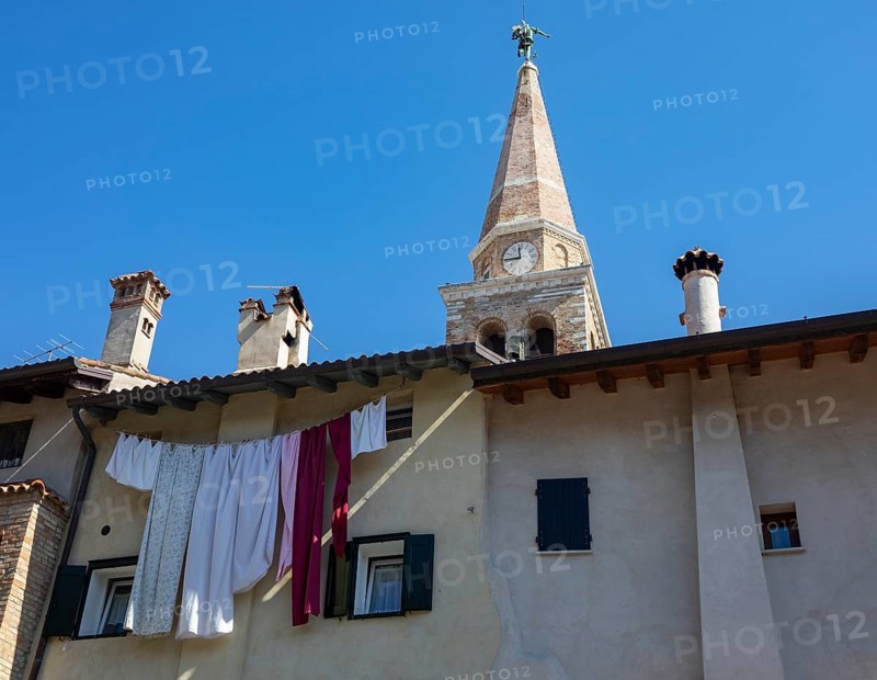 Laundry hanging to dry on a house facade with the Basilica of Sant Eufemia