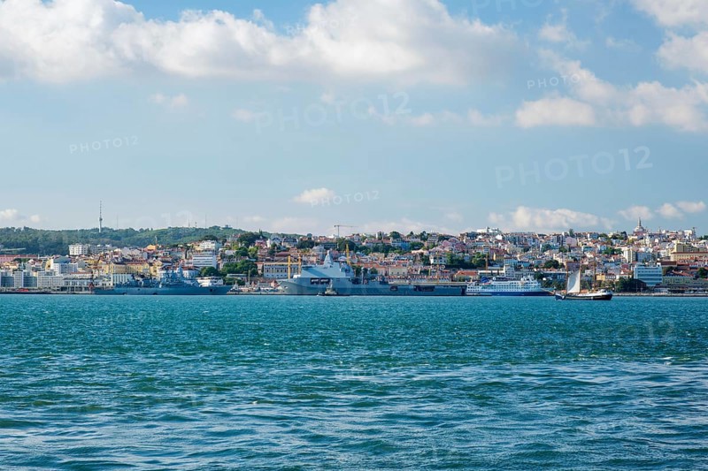 View of Tagus river with tourist boat and moored NATO warships in Lisbon