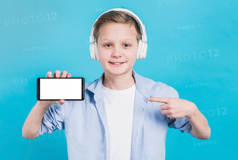 Close up boy wearing headphone head pointing her finger toward mobile phone with blank screen