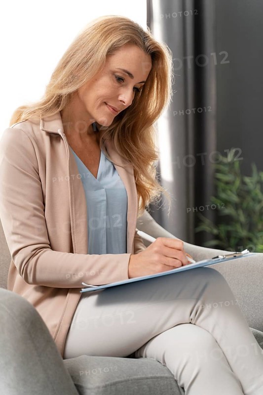 Mid shot woman therapist writing clipboard