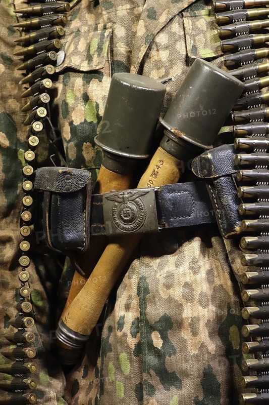 Close up of two WW2 stielhandgranaten tucked under pants belt of German SS soldier carrying machine gun ammunition belt