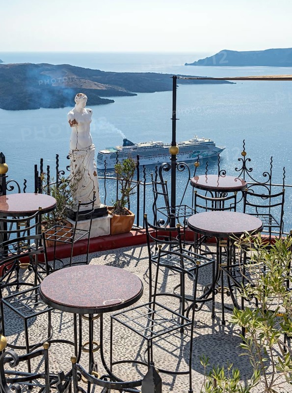 View of sea and cruise ship from terrace with chairs and table