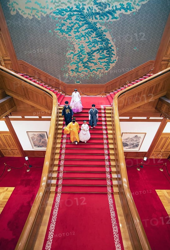 Visitors in traditional dress on the red staircase in the Blue House or Cheongwadae