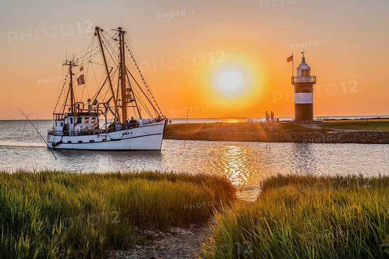 Crab cutter with the Kleiner Preusse lighthouse at the Sielhafen harbour at sunset
