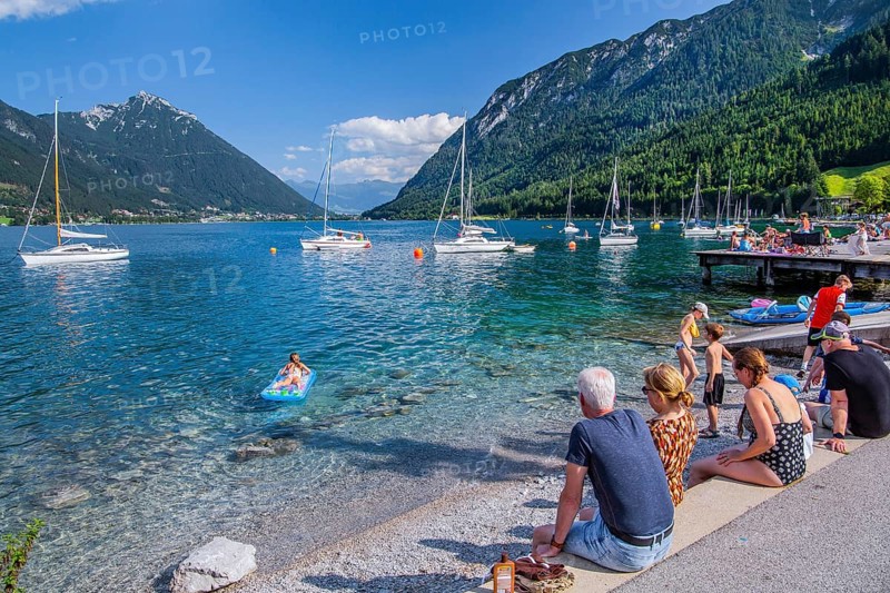 Holidaymakers on the lake promenade with sailing boats