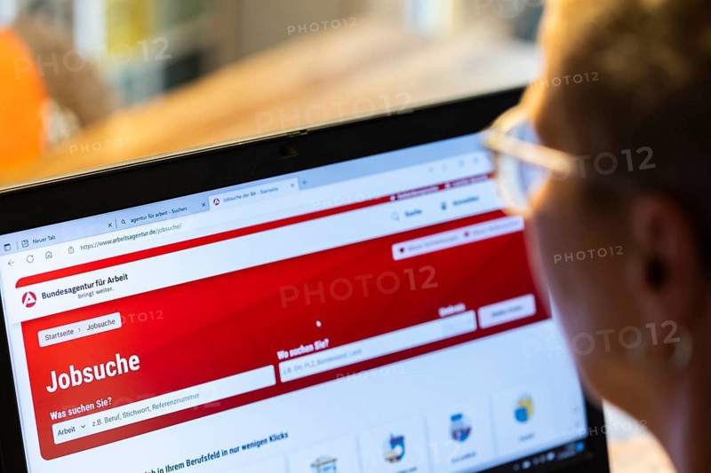 Woman with glasses looking for a job sits at home in front of her notebook and checks the internet site of the Federal Employment Agency for job offers