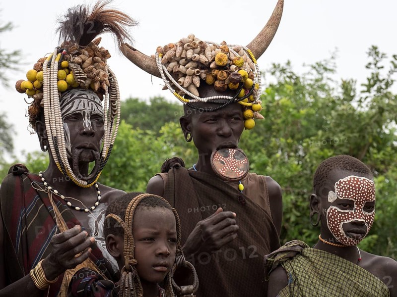 Women and children of the Mursi tribe with headdress and lip plate