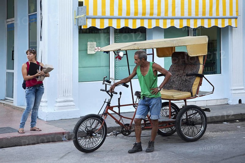 Man with three-wheeled bicycle taxi waiting for tourists in Cienfuegos