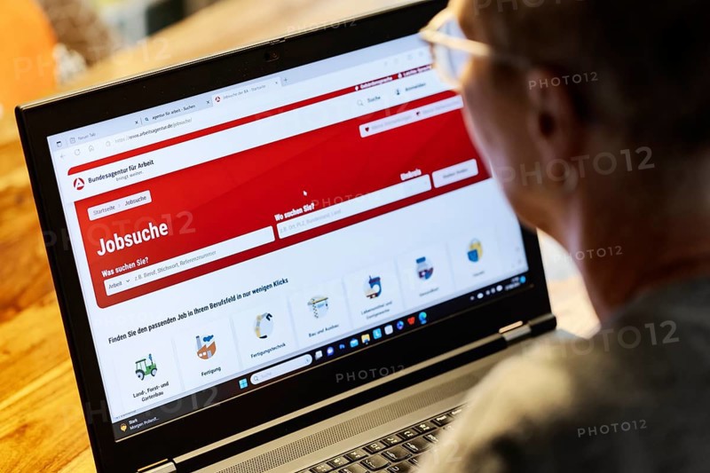 Woman with glasses looking for a job sits at home in front of her notebook and checks the internet site of the Federal Employment Agency for job offers