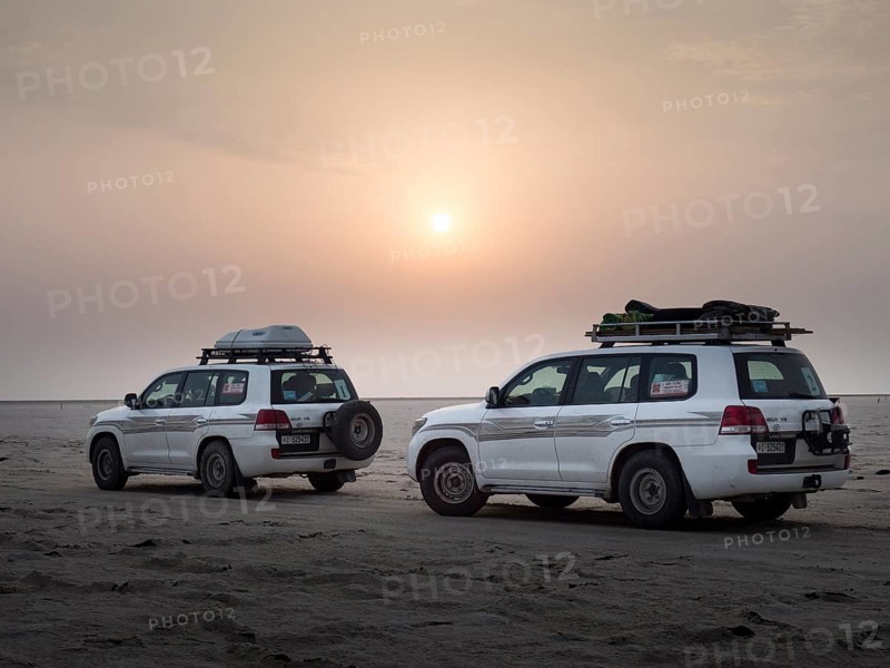 Tourists in off-road vehicles driving on salt desert at sunrise