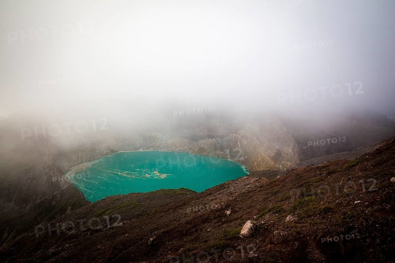 Fog over crater with turquoise crater lake