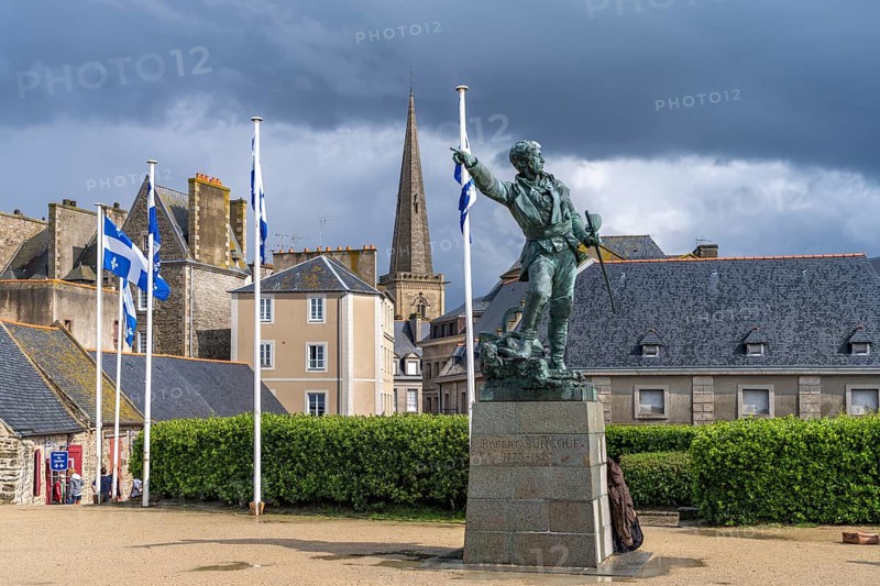 Statue of the privateer Robert Surcouf in front of the old town with the tower of St Vincent Cathedral