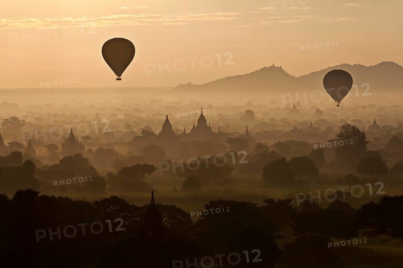 Hot air balloons over landscape with stupas