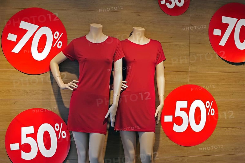Discount notices showing deductions in shop window of clothes store during the summer sales in shopping street