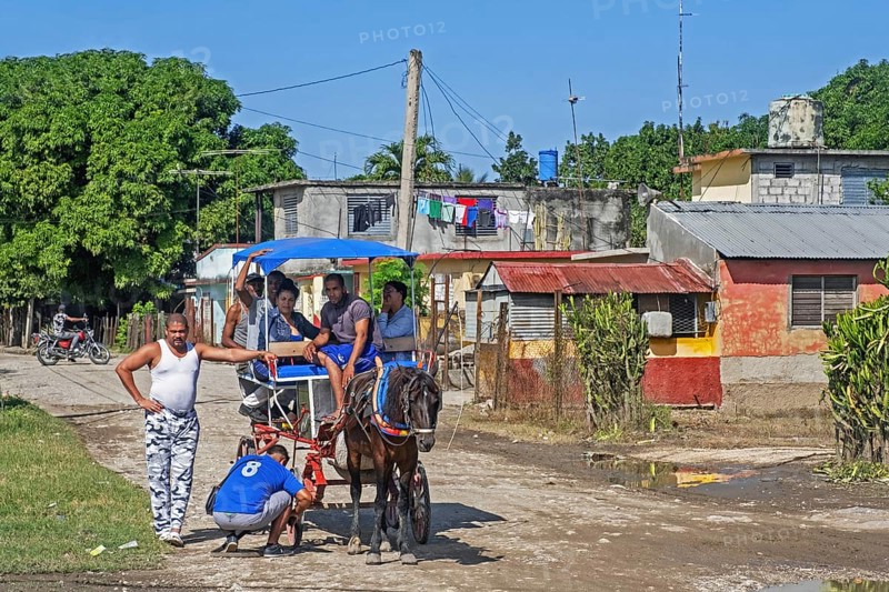 Cuban repairing horse-drawn taxi carriage in rural village in the Sierra Maestra
