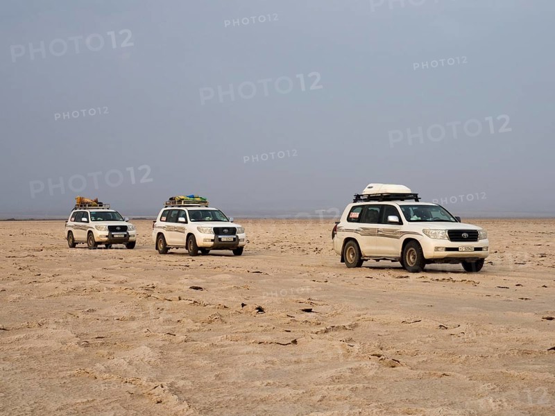 Tourists in off-road vehicles driving on salt desert